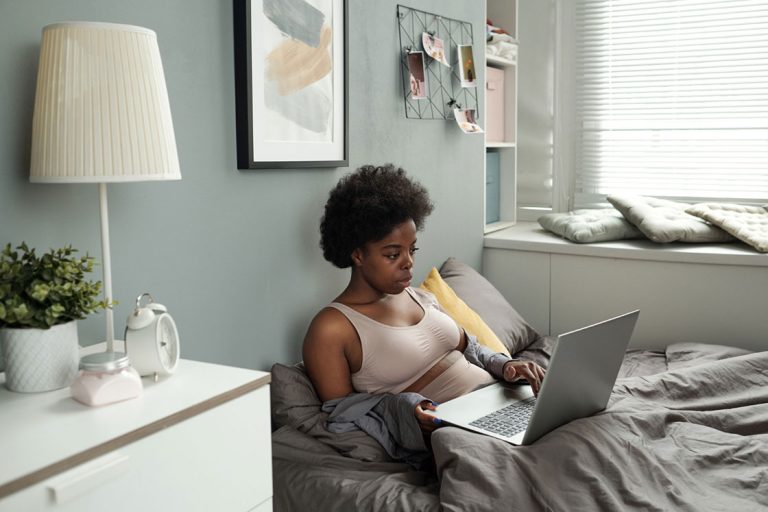 woman sitting in bed looking laptop screen